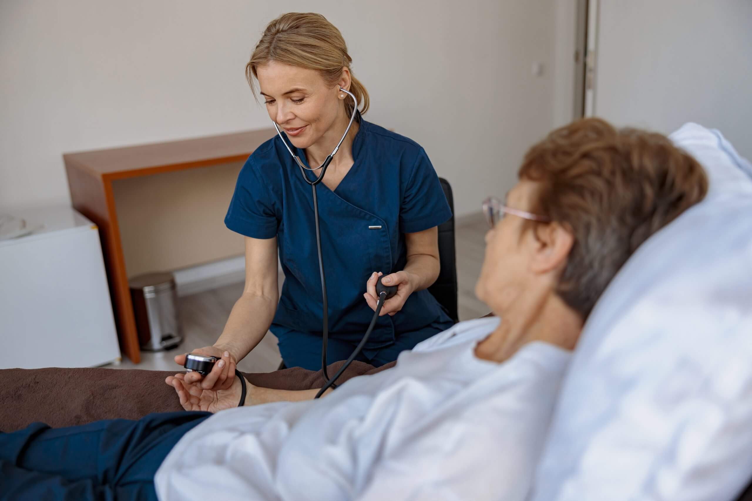 Nurse checking blood pressure of senior woman